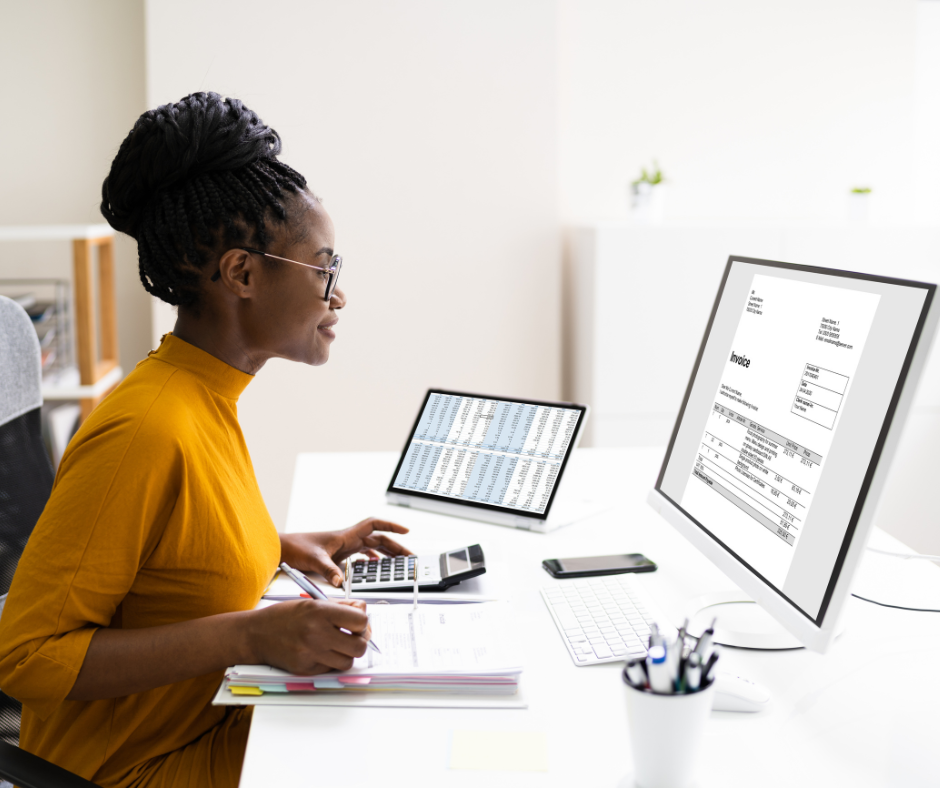 a woman sitting at a desk with a computer and a calculator